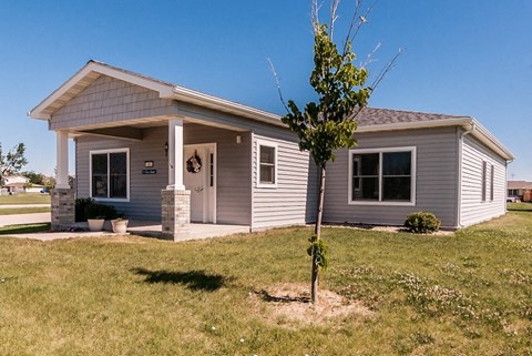 a small gray house with a tree in front of it