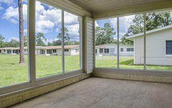 a large screened in porch with large windows overlooking a field and houses