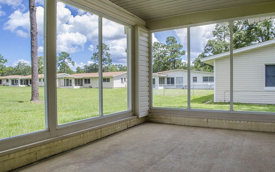a large screened in porch with large windows overlooking a field and houses