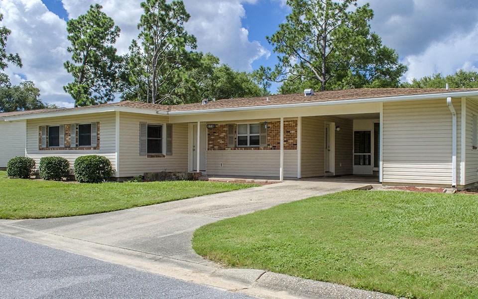 a white and brown house with a driveway and grass
