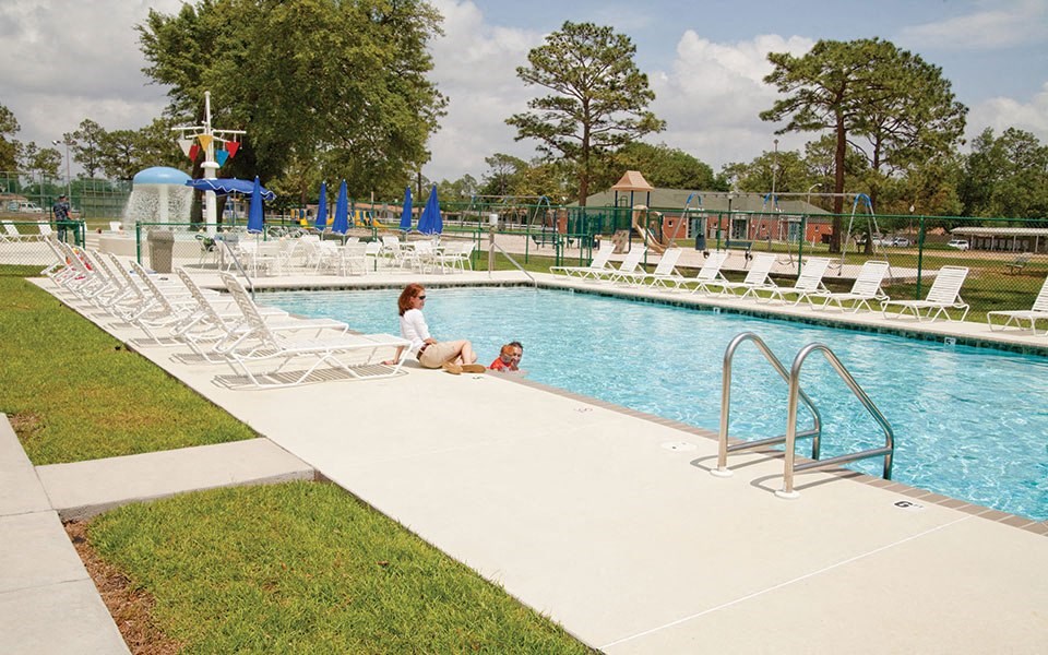 a woman and a child sitting by a swimming pool