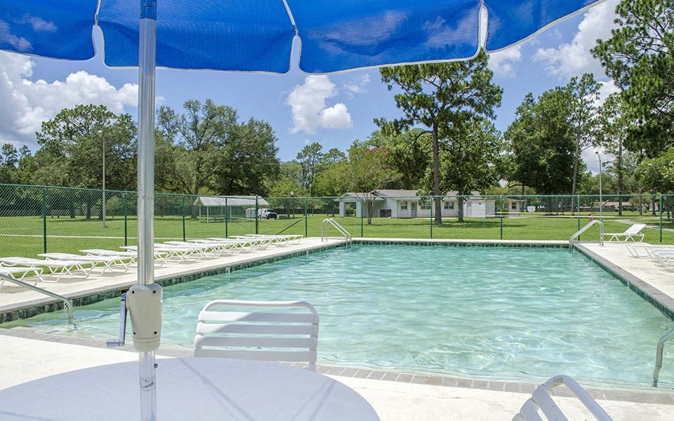a swimming pool with a blue umbrella and white chairs