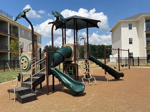 A playground with a green slide and a black metal structure.