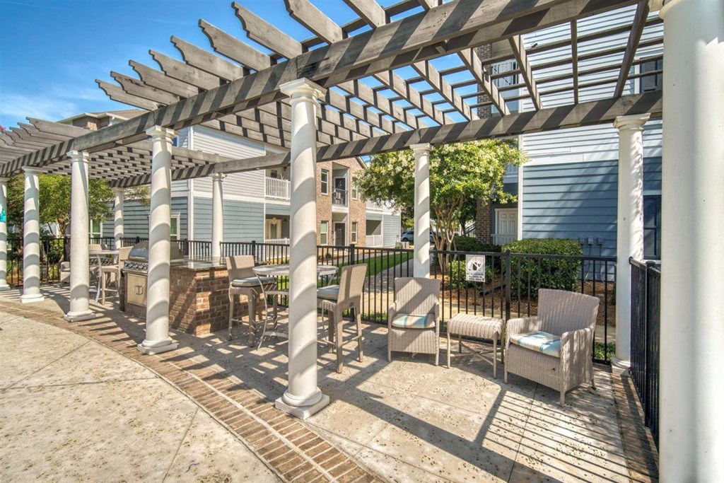 A patio with a white pergola and chairs.at Cypress River, Ladson, SC, 29456