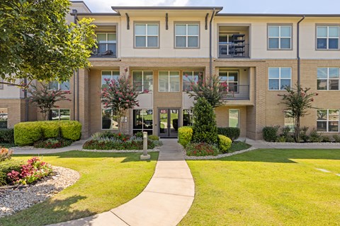 A building with a green lawn in front at The Preserve at Preston Trails Apartments, Cedar Hill, TX