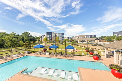 A pool with a slide and a building in the background at The Preserve at Preston Trails Apartments, Cedar Hill, TX, 75104
