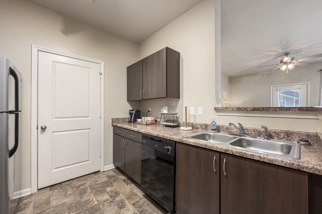 A kitchen with a white door, brown cabinets, and a tiled floor.