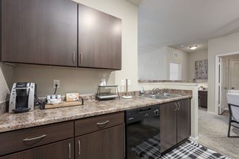 A kitchen with dark brown cabinets and granite countertops.