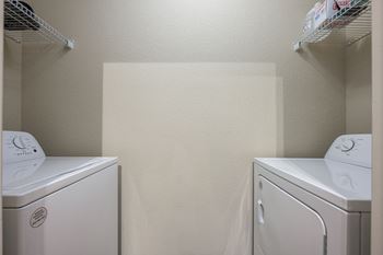 Two white front loading washing machines in a small laundry room.