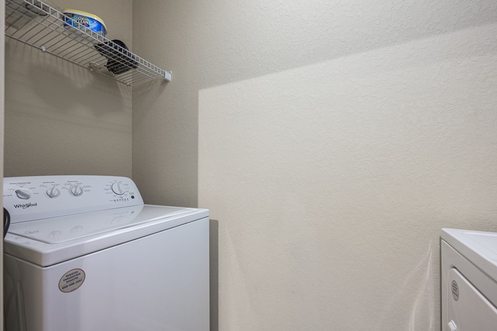 A white dryer is on the left in a small laundry room.