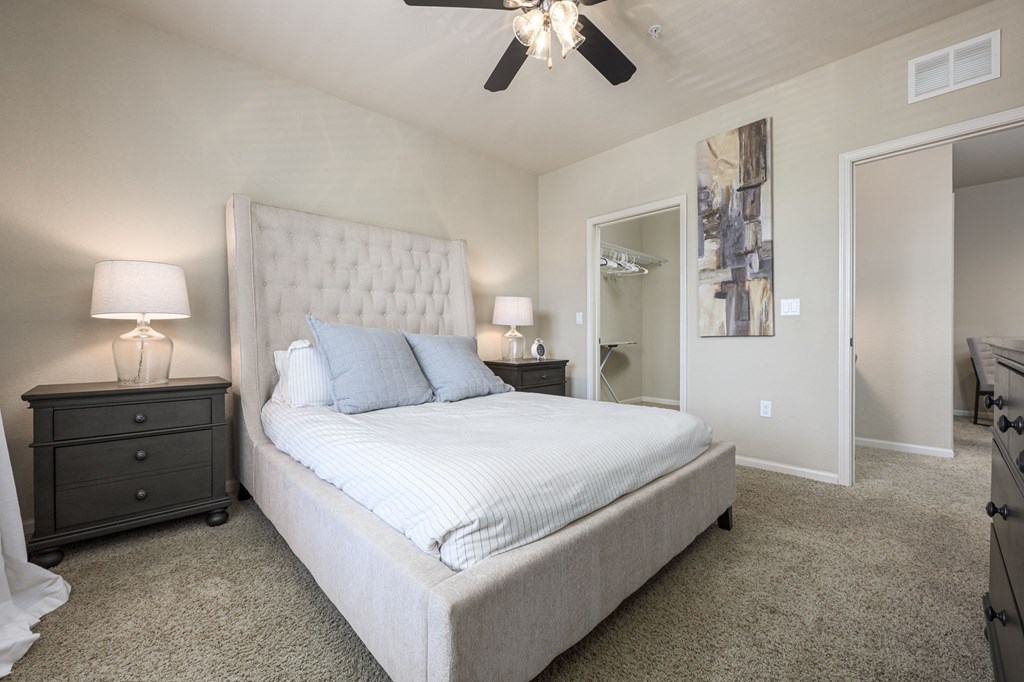 A bedroom with a large bed and a ceiling fan.