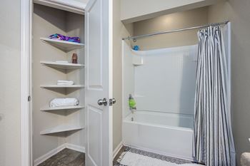 A white bathroom with a white tub and a white shower curtain.