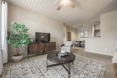 A living room with a black coffee table and a tv on a cabinet.