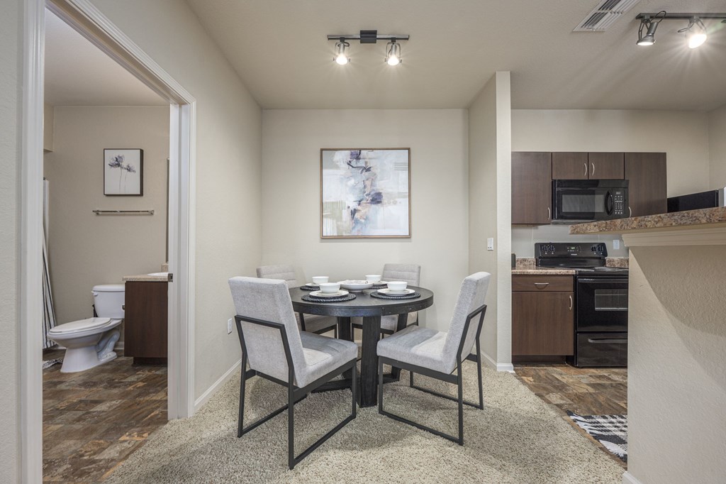 A dining room with a table set for two and a kitchen area in the background.