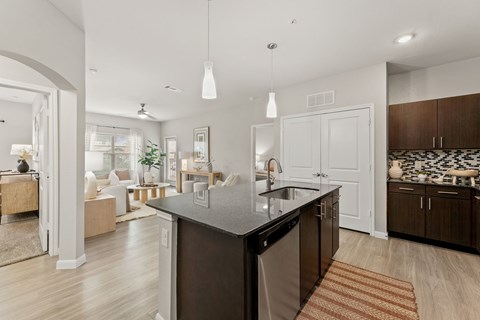 A modern kitchen with a dark countertop and a dining area with a table and chairs.