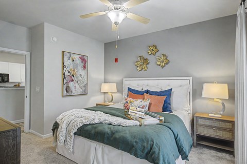 A bedroom with a bed, nightstands, and a ceiling fan.