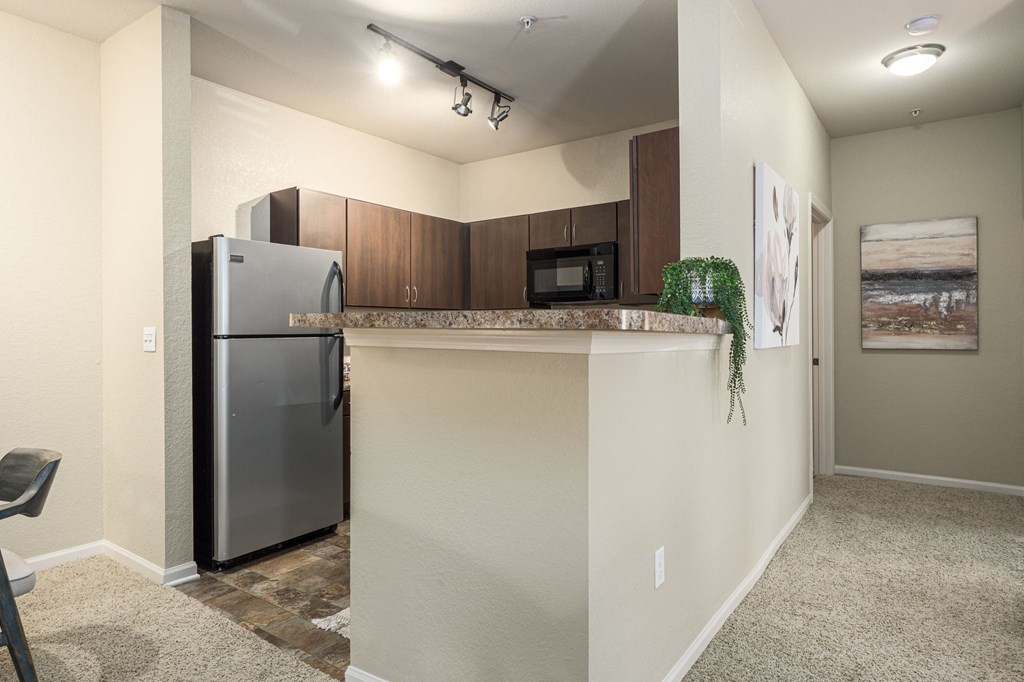 A kitchen area with a refrigerator, microwave, and a countertop.