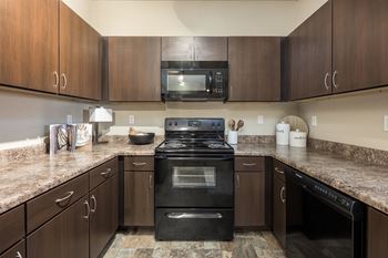 A kitchen with a black stove top oven and wooden cabinets.