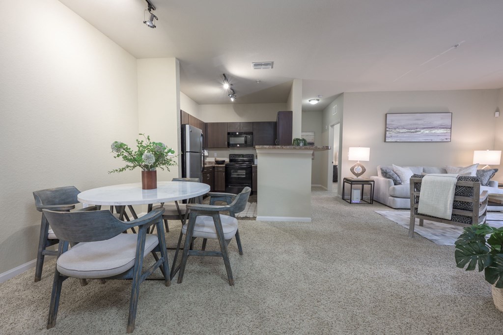 A modern living room with a dining table and grey chairs.