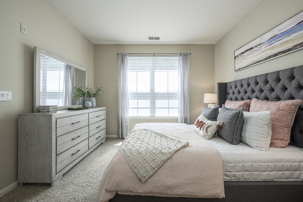 A bedroom with a large bed and a dresser with a mirror.