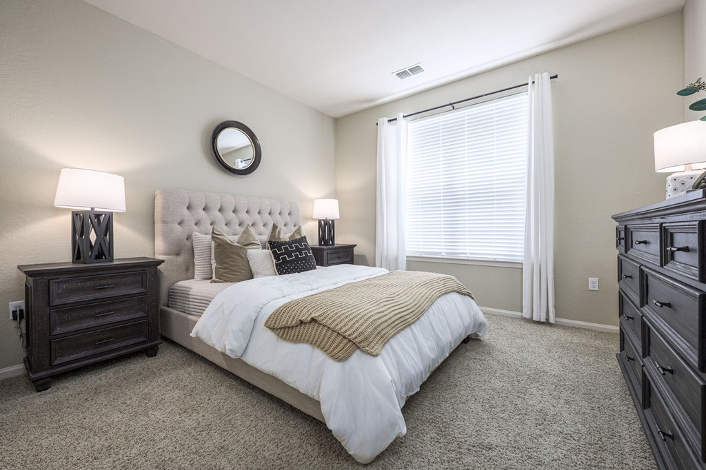 A bedroom with a large bed, a dresser, and a mirror on the wall.
