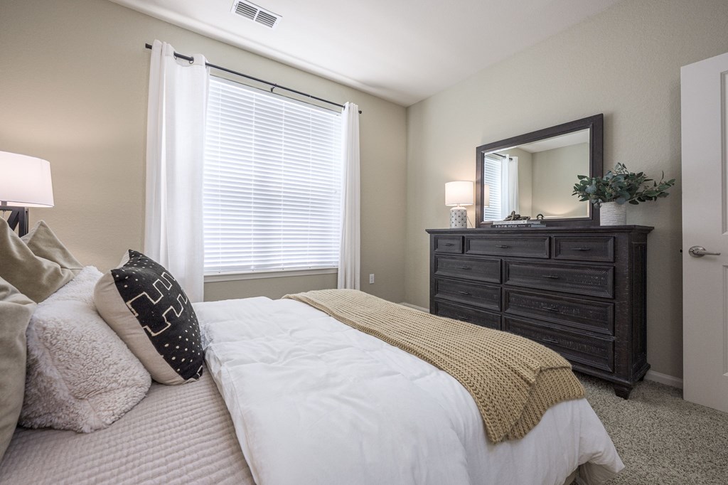 A bedroom with a bed, dresser, and mirror.