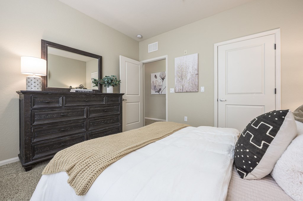 A bedroom with a large bed and a wooden dresser.