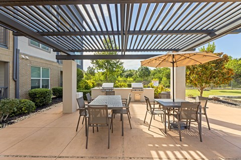A patio with a table and chairs under a metal roof at The Preserve at Preston Trails Apartments, Cedar Hill, TX