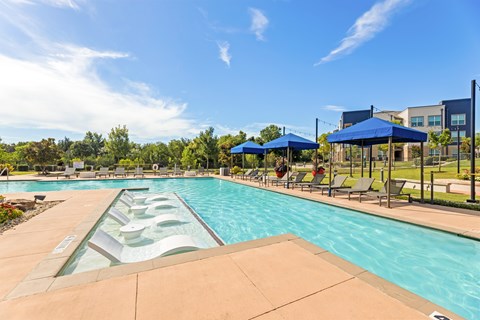 A large outdoor swimming pool with a slide and sunshades at The Preserve at Preston Trails Apartments, Cedar Hill 75104