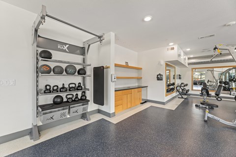 A gym with a weight rack and exercise equipment at The Preserve at Preston Trails Apartments, Cedar Hill, Texas