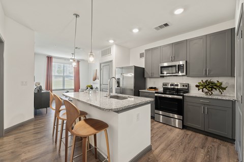 A modern kitchen with wooden chairs and stainless steel appliances.
