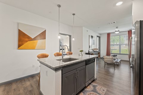 A modern kitchen with a large island and a painting on the wall at The Preserve at Preston Trails Apartments, Cedar Hill, Texas