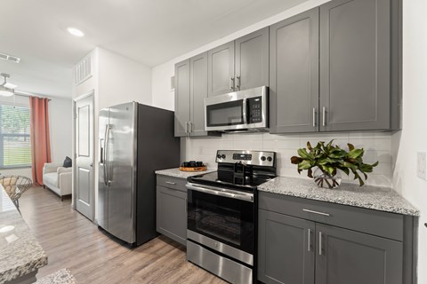A kitchen with a refrigerator, oven, and microwave at The Preserve at Preston Trails Apartments, Cedar Hill