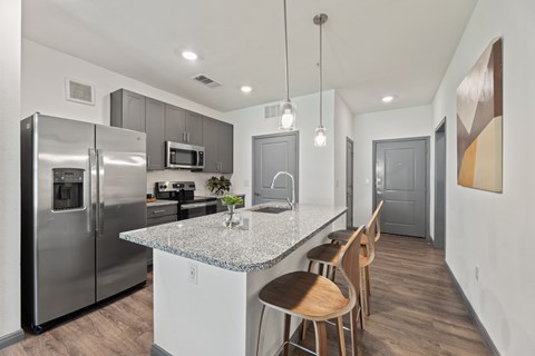 A kitchen with a granite countertop and stainless steel appliances at The Preserve at Preston Trails Apartments, Texas, 75104