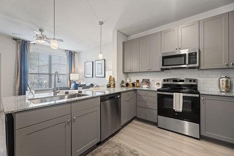 A modern kitchen with a stainless steel oven and grey cabinets.
