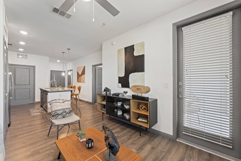 A modern living room with a wooden floor and a ceiling fan at The Preserve at Preston Trails Apartments, Cedar Hill 75104