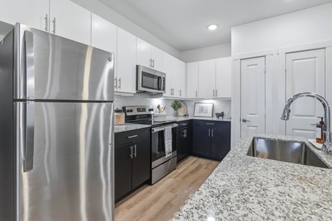A modern kitchen with a stainless steel refrigerator and black cabinets.