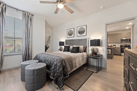 A bedroom with a bed, a ceiling fan, and a mirror.
