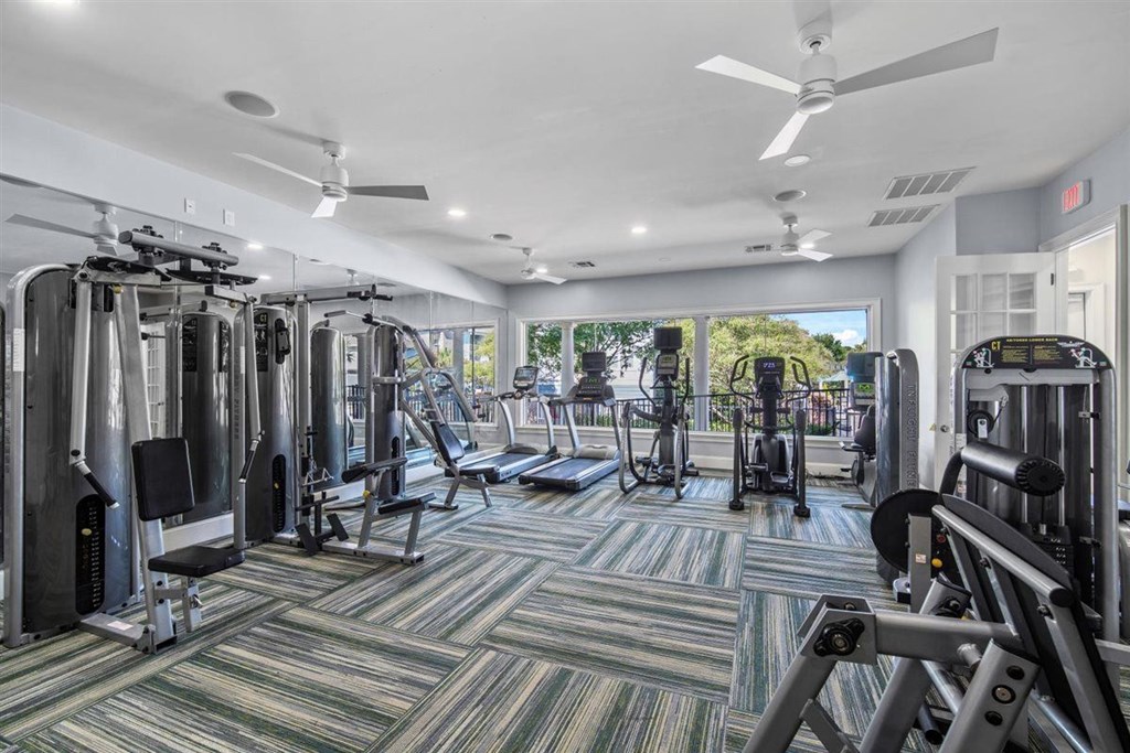 A gym with a variety of equipment including treadmills, weights, and a ceiling fan.at Cypress River, Ladson, SC, 29456