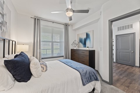 A bedroom with a bed, dresser, and a ceiling fan at The Preserve at Preston Trails Apartments, Cedar Hill, TX