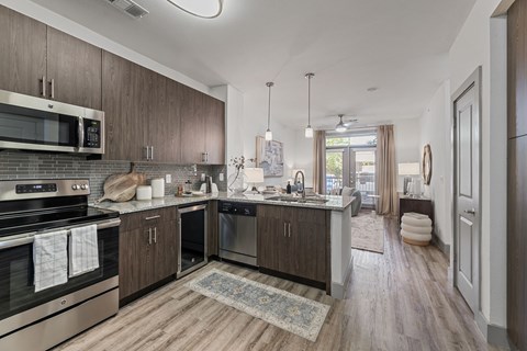 A modern kitchen with dark wood cabinets and stainless steel appliances.