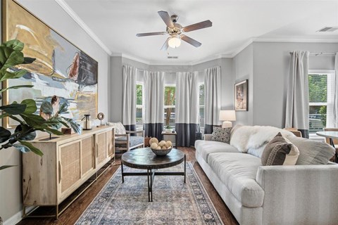 A living room with a large painting on the wall and a ceiling fan.