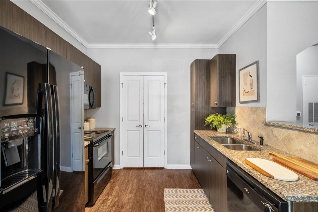 A kitchen with a black fridge and wooden floors.at Cypress River, Ladson, SC