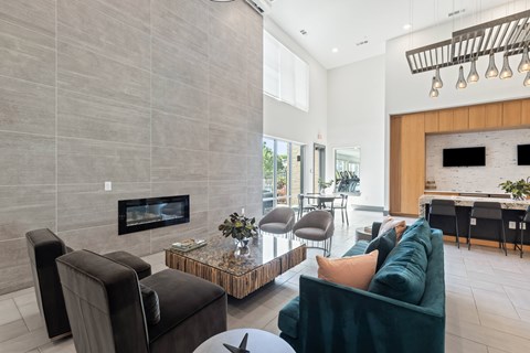 A modern living room with a fireplace and a green couch at The Preserve at Preston Trails Apartments, Cedar Hill, Texas