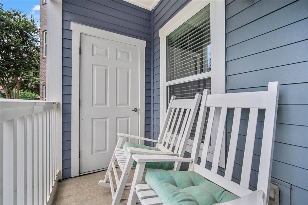 A white chair is placed on a green cushion on a porch.at Cypress River, Ladson, 29456