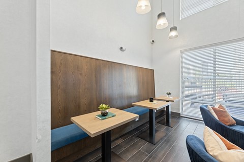 A modern dining area with a wooden bench and a table with a vase of flowers on it at The Preserve at Preston Trails Apartments, Texas