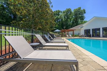A row of sun loungers are on the edge of a pool.