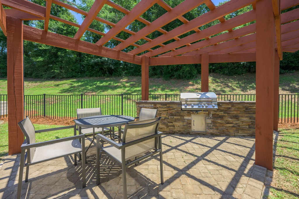 A patio with a table and chairs under a pergola.at Spring Creek Apartments, Florida, 32536