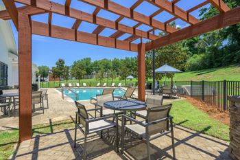 A patio with a table and chairs under a pergola.