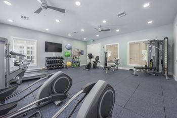 A spacious gym with a variety of equipment including treadmills, exercise balls, and weight machines.